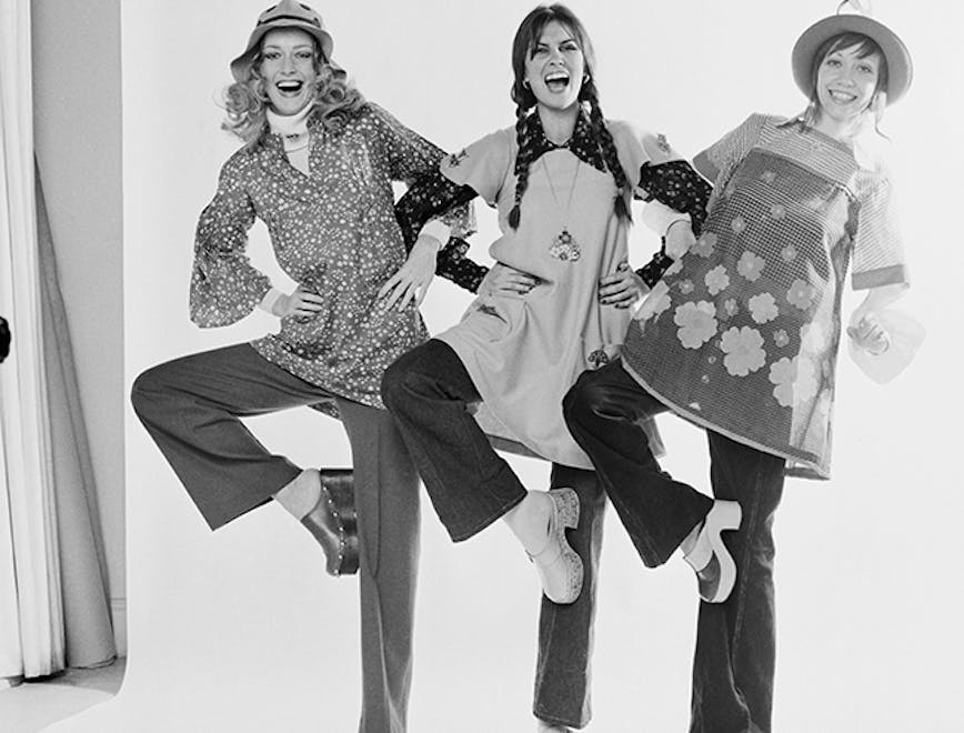 black & white huty19857 1972 exp 1972 580 fr 4 three people women only full length eye contact posed indoors fashion model backdrop studio shot fashion shoot tunic smock patterned arm in arm formation laughing smiling platform shoe clogs person human clothing apparel dance pose leisure activities sleeve