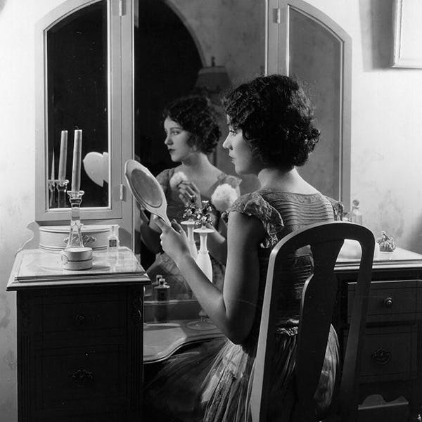 black & white;format portrait;reflection;female;mirror;make up;reflection;film;film actress;silent era;stars at home;film make up;personality;american;m/cin/port/wray/fay room indoors person human furniture dressing room hair