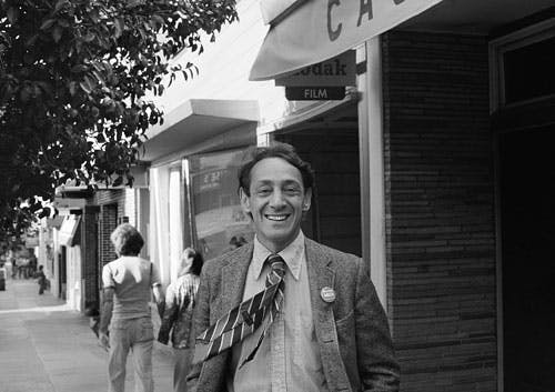 harvey milk in front of his castro street camera store circa 1977 person human tie accessories accessory clothing suit coat overcoat path